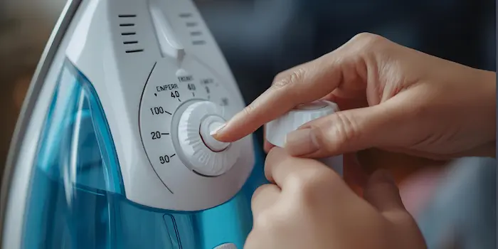 Close-up of a person adjusting the temperature dial on a steam iron